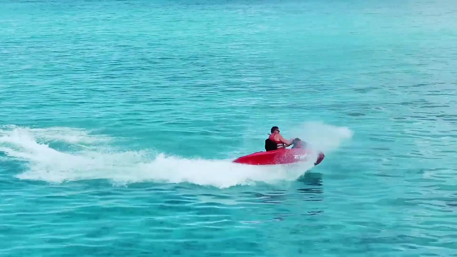 Red EWAVE V1 jetboat throwing spray across turquoise water in the Maldives