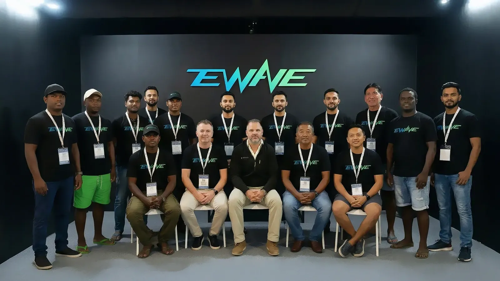 The EWAVE team in Dubai in black EWAVE shirts in front of a lit EWAVE logo